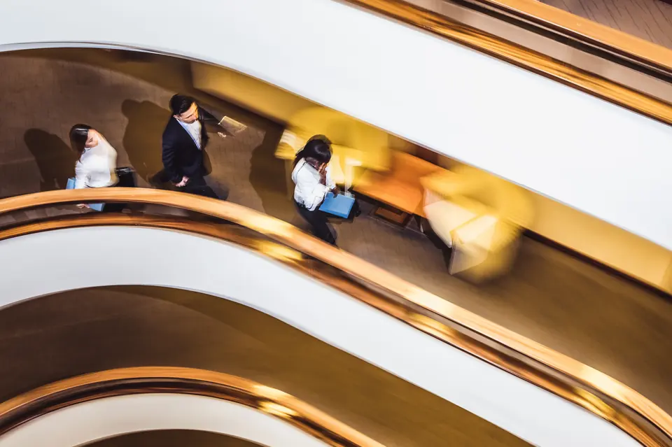 People walking through a sunlit office atrium