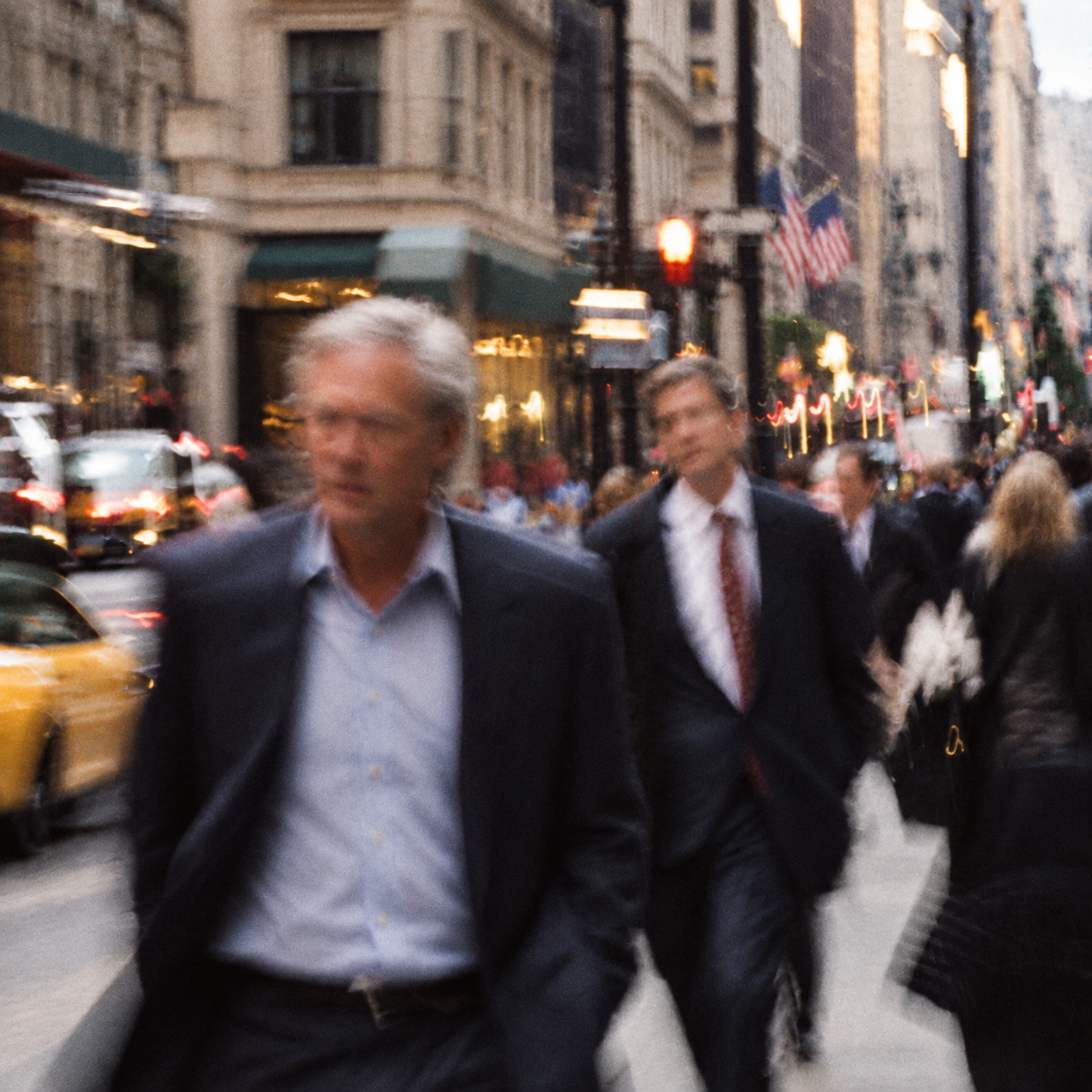 Suited men walking along a city street, captured in vintage color with film grain and motion blur